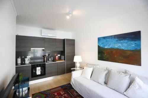 Central Lisbon Luxury Apartment في لشبونة: غرفة معيشة مع أريكة بيضاء ومطبخ