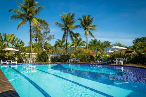a swimming pool at a resort with palm trees at Pousada da Condessa in Paraty