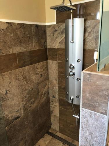 a shower in a bathroom with brown tiles at Sosua Inn Hotel in Sosúa