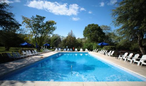 a swimming pool with white chairs and a blue sky at Howard Johnson Hotel & Spa Villa General Belgrano in Villa General Belgrano