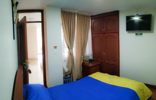a bedroom with a blue and yellow bed and a tv at Hotel Casa de Peregrinos in Ipiales