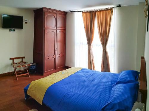 a bedroom with a blue bed and a large window at Hotel Casa de Peregrinos in Ipiales