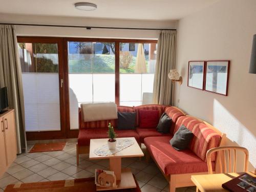 a living room with a red couch and a table at Ferienwohnung Niklas inklusive Bad Hindelang Plus in Bad Hindelang