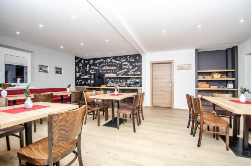 a restaurant with tables and chairs and a chalkboard wall at Appart-Pension Schnöll in Mittersill
