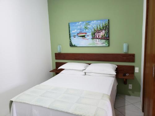 um quarto com uma cama branca e uma pintura na parede em Pousada Barra Nativa em Florianópolis