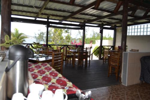 ein Restaurant mit einem Tisch, Stühlen und Fenstern in der Unterkunft Villa Espanhola Bilene in Vila Praia Do Bilene