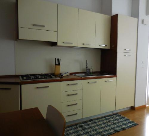 a kitchen with white cabinets and a stove and a table at Olive Tree House in Riva del Garda