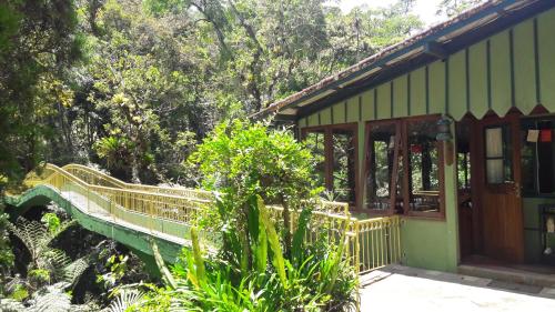 a green house with a porch and trees at Refúgio Ecológico Amadamata in Nova Friburgo