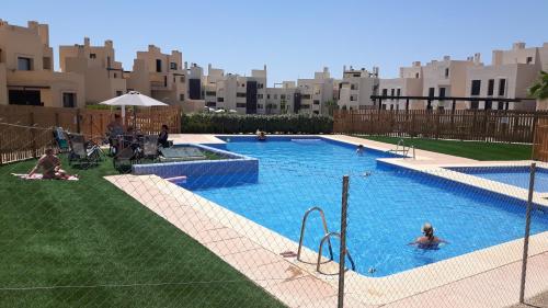 a swimming pool with people in it with buildings in the background at Casa Patrick in Murcia