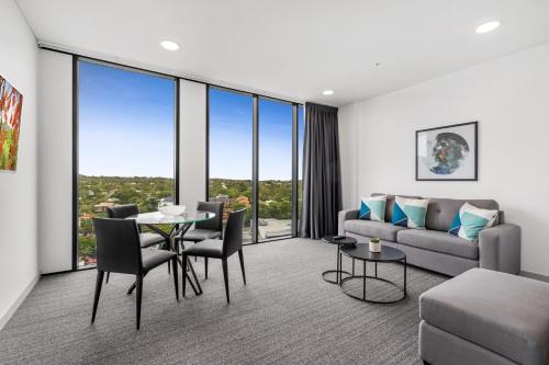 a living room with a couch and a table and chairs at Essence Suites Taringa in Brisbane