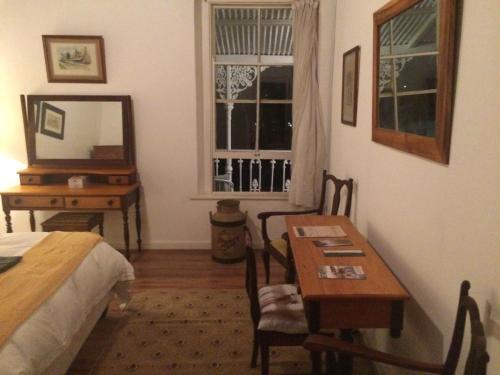 a bedroom with a bed and a table and a mirror at Towerzicht Guest House in Ladismith