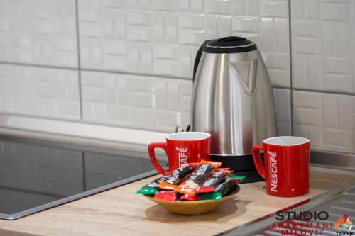 a counter with two coffee cups and a bowl of candy at Studio apartmani Milović in Trebinje