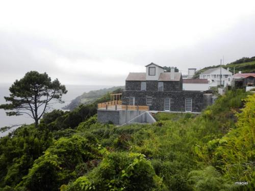 uma casa numa colina com o oceano ao fundo em Casa da Aguada em Lajes do Pico