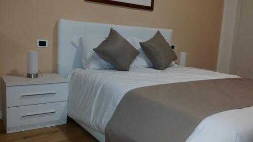 a white bed with two pillows and a night stand at Villa Cristalli clinica pc in Piacenza