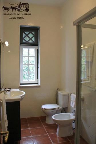 a bathroom with a toilet and a sink and a window at Camping Lamego Douro Valley in Lamego