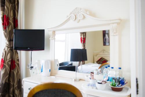 a bedroom with a bed and a desk with a mirror at Queensbridge Hotel in Aberystwyth