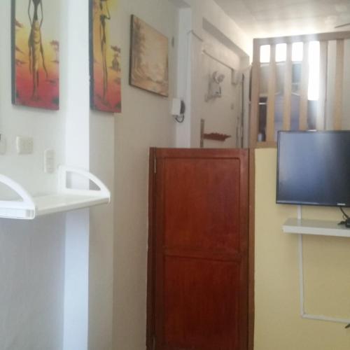 a room with a tv and a wooden door at El Canadiense in Canoas De Punta Sal