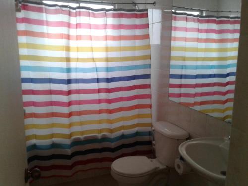 y baño con cortina de ducha colorida y aseo. en Casa Bahia Inglesa, en Bahía Inglesa