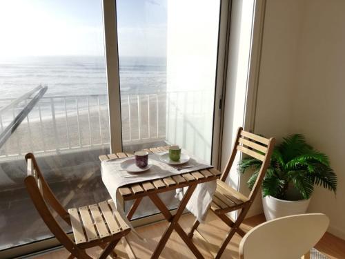 a table and chairs in front of a large window at Mar Beach Apartment in Póvoa de Varzim