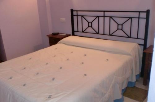 a bedroom with two beds with white sheets at Hostal Restaurante La Ilusion in El Palmar
