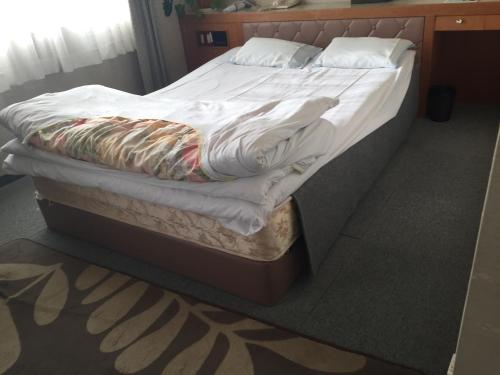 Katsuura Seaside Hotel في ناتشيكاتسورا: سرير غير مرتب مع شراشف ووسائد بيضاء