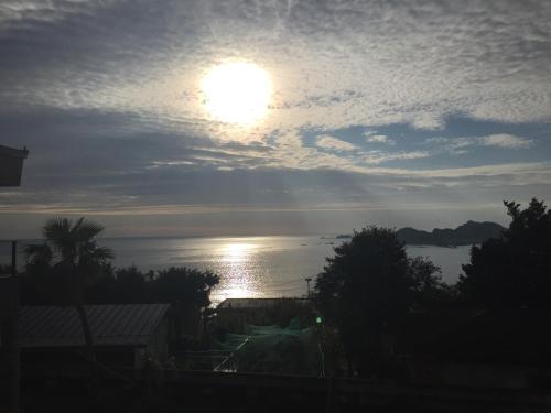 einen Blick auf das Meer mit der Sonne am Himmel in der Unterkunft Katsuura Seaside Hotel in Nachikatsuura