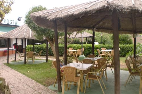 a group of tables and chairs under a straw umbrella at Hostal Restaurante La Ilusion in El Palmar