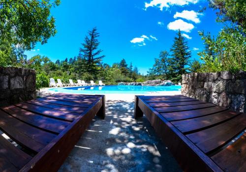 a swimming pool with two wooden benches next to it at Hotel Las Cascadas in La Cumbrecita