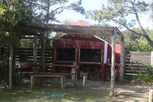 a shed with a red roof and a bench at Los Pecados de la Viuda in Punta Del Diablo