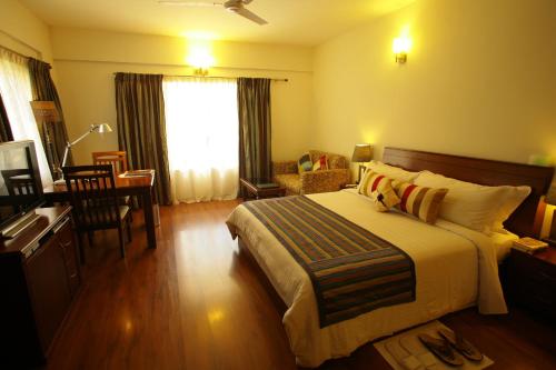 1 dormitorio con 1 cama, 1 mesa y 1 silla en juSTa Off MG Road, en Bangalore