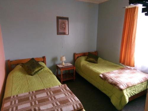 1 dormitorio con 2 camas y mesa con lámpara en Hotel Ventura, en Chile Chico