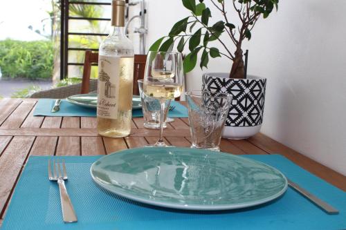 a wooden table with a plate and a bottle of wine at COLIBRIS PARADISE LA MARINA in Le Gosier