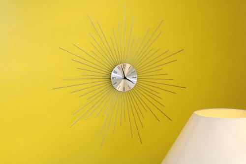 a sunburst clock on a yellow wall at COLIBRIS PARADISE LA MARINA in Le Gosier