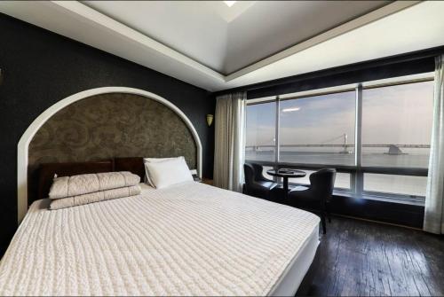 a bedroom with a bed and a view of the ocean at Bridge Hotel in Busan