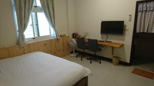a bedroom with a bed and a desk with a television at Ho Hai Yan Homestay in Chenggong