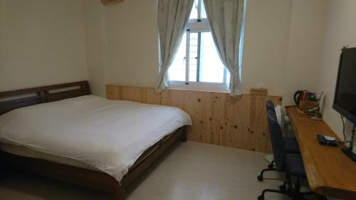 a bedroom with a bed and a desk and a window at Ho Hai Yan Homestay in Chenggong