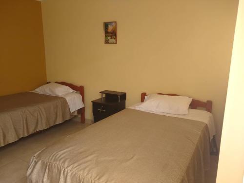 a room with two beds and a table and a picture on the wall at Hospedaje Golden Inn in Camaná