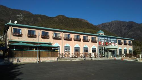 a large building with a building with mountains in the background at Fujibou Hotel in Fujikawaguchiko