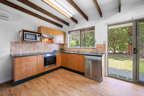 a kitchen with wooden cabinets and a large window at NRMA South West Rocks Holiday Park in South West Rocks
