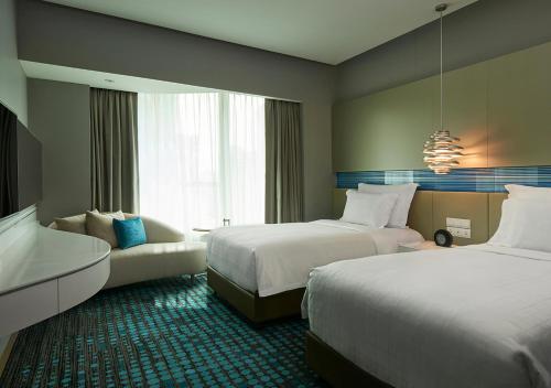 a hotel room with two beds and a couch at Pullman Kuala Lumpur City Centre Hotel & Residences in Kuala Lumpur