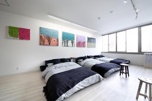 três camas num quarto com pinturas na parede em Culinary Bed&Art 402 em Hamamatsu