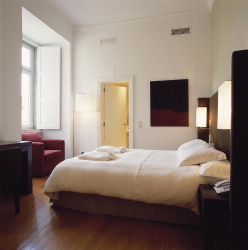a bedroom with a large bed and a red couch at York House Lisboa Hotel in Lisbon