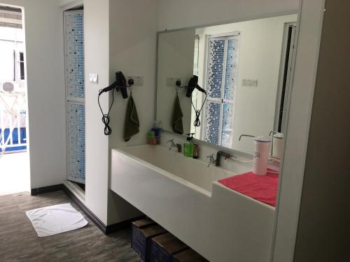 baño con lavabo y espejo grande en Signel Hostel, en Kota Kinabalu
