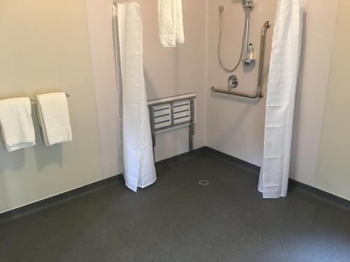 a bathroom with a shower with white curtains in it at Forest View Franz Josef in Franz Josef