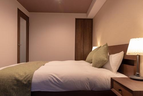 a bedroom with a large white bed and a lamp at Kyoto Riverview House Kyoraku in Kyoto