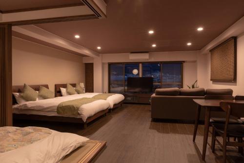 a bedroom with two beds and a couch and a television at Kyoto Riverview House Kyoraku in Kyoto