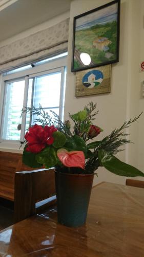 a vase with flowers sitting on a table at Ho Hai Yan Homestay in Chenggong