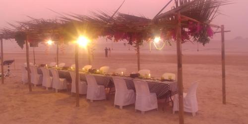 a table with white chairs and lights on the beach at Khao Tao Beach Lodge Old Siam in Hua Hin