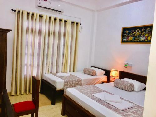 a small room with two beds and a window at Mindana Residence in Anuradhapura