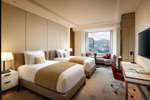a hotel room with two beds and a television at Lotte Hotel Seoul in Seoul